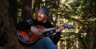 Sergius Sergius Gregory playing guitar in the Tongass Forest
